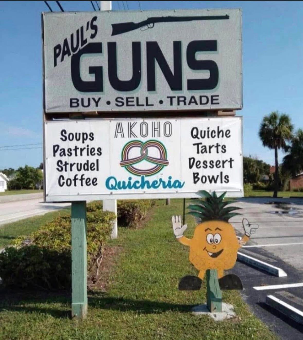 AKOHO and Paul's Guns sign on US 1 with a waving pineapple mascot